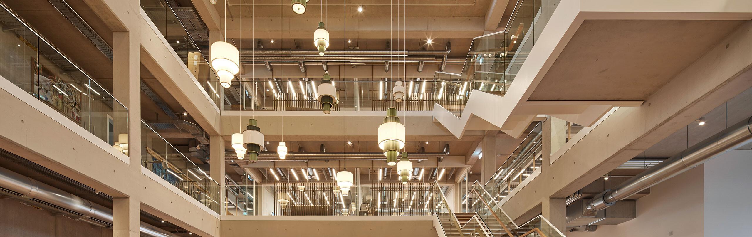 Lineare LED-Pendelleuchte mit Direkt-Indirekt-Lichtanteil über einem modernen Büro-Arbeitsplatz für eine ergonomische und ASR-konforme Beleuchtung.